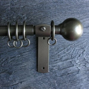 a slim bronze metal curtain pole with ball finials