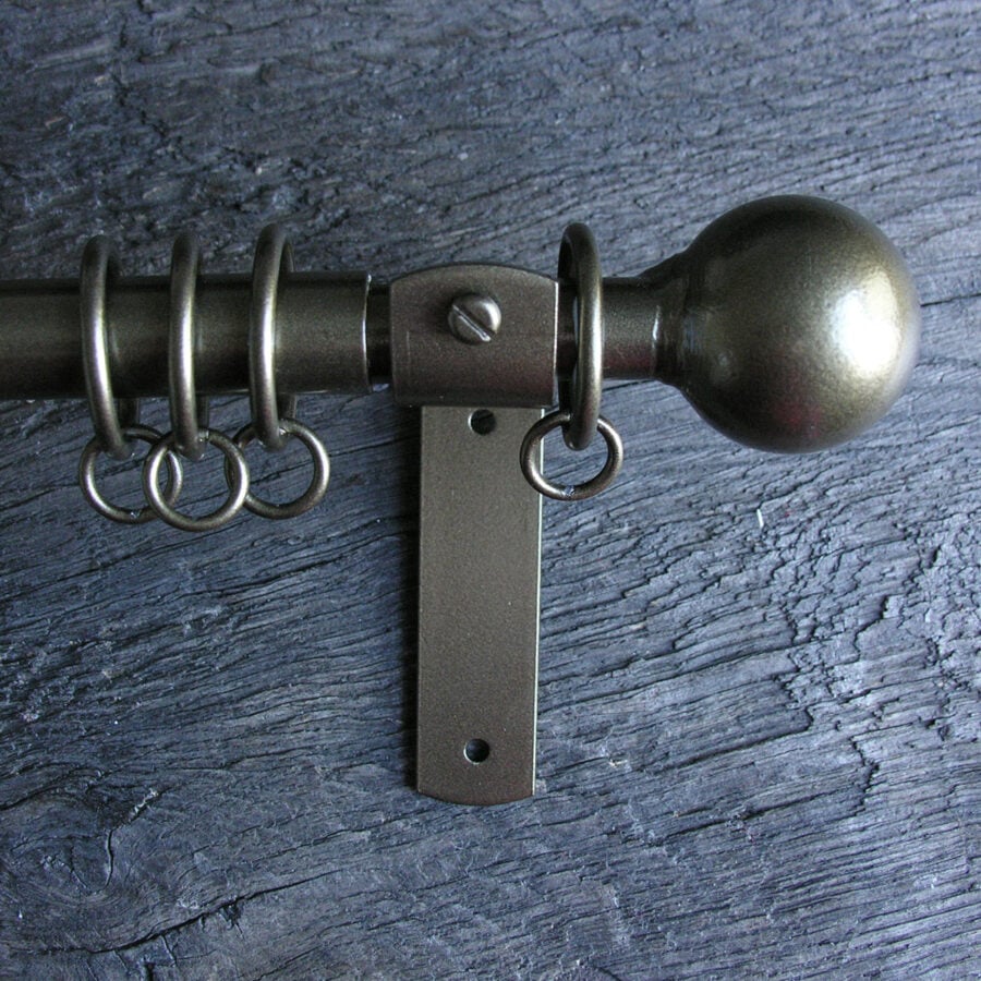 a slim bronze metal curtain pole with ball finials