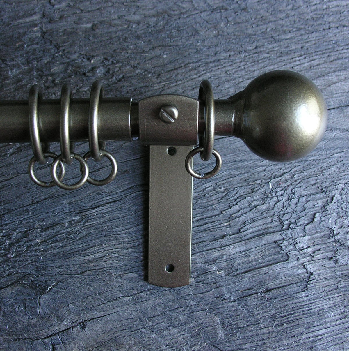 a slim bronze metal curtain pole with ball finials