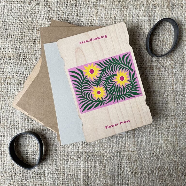 An opened pocket-sized flower press showing cardboard layers