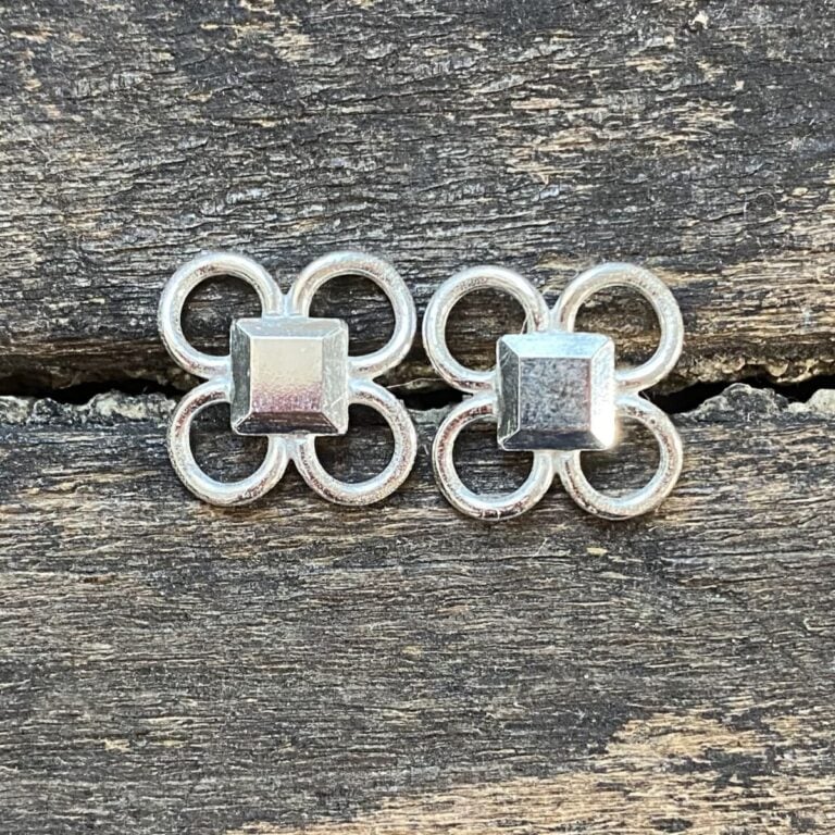 Silver quatrefoil earrings on a wooden background