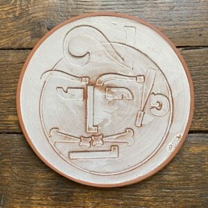 Round plate with letterpress blocks impressed into the clay to make a face. By John Ingledew.