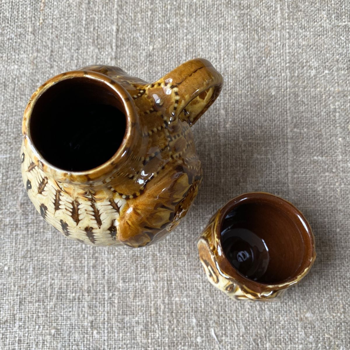 Carole Glover slipware glazed Owl Jug against a wooden background