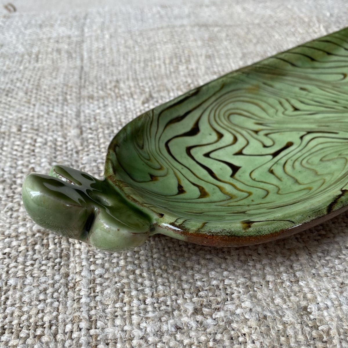 Patia Davis extra long oval platter with green glaze on linen backcloth