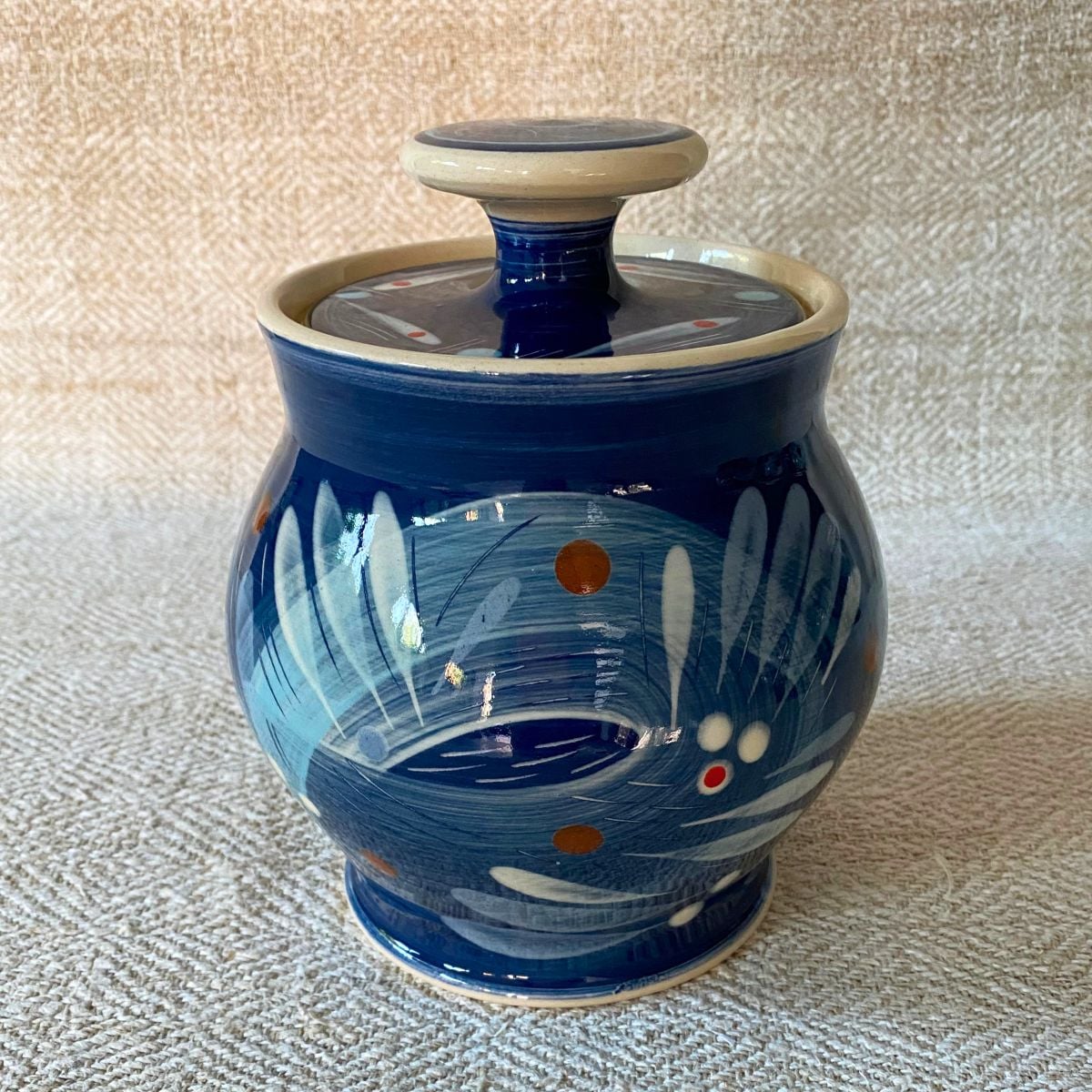 RAMP Ceramics earthenware caddy jar in a blue abstract design on a cream textile backdrop.