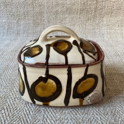 White glazed butter dish with lid against a fabric background