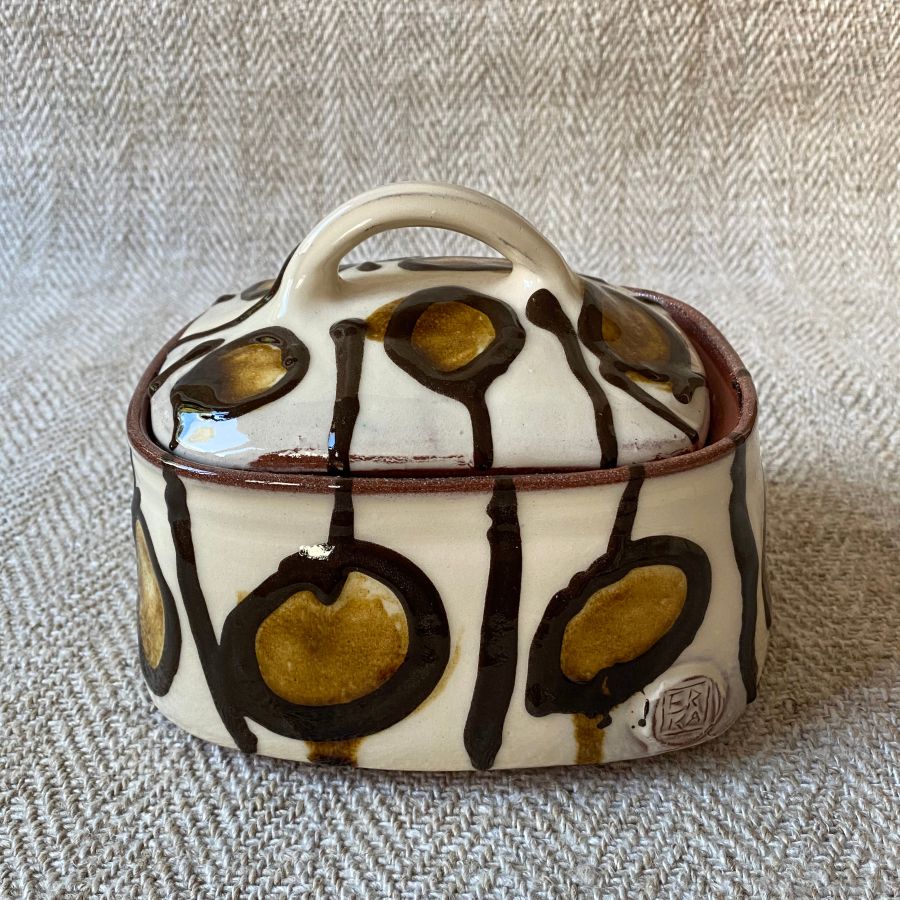 White glazed butter dish with lid against a fabric background